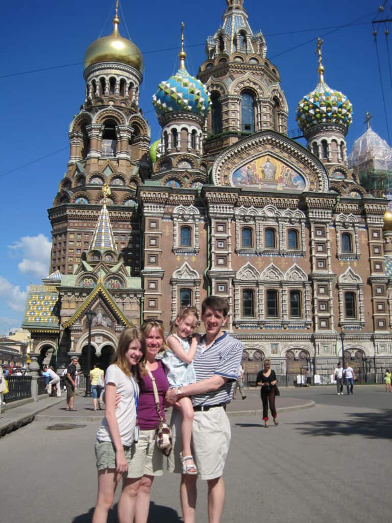 Man holding small girl standing beside woman and older girl outside Church of Our Saviour on Spilled Blood in St. Petersburg, Russia.