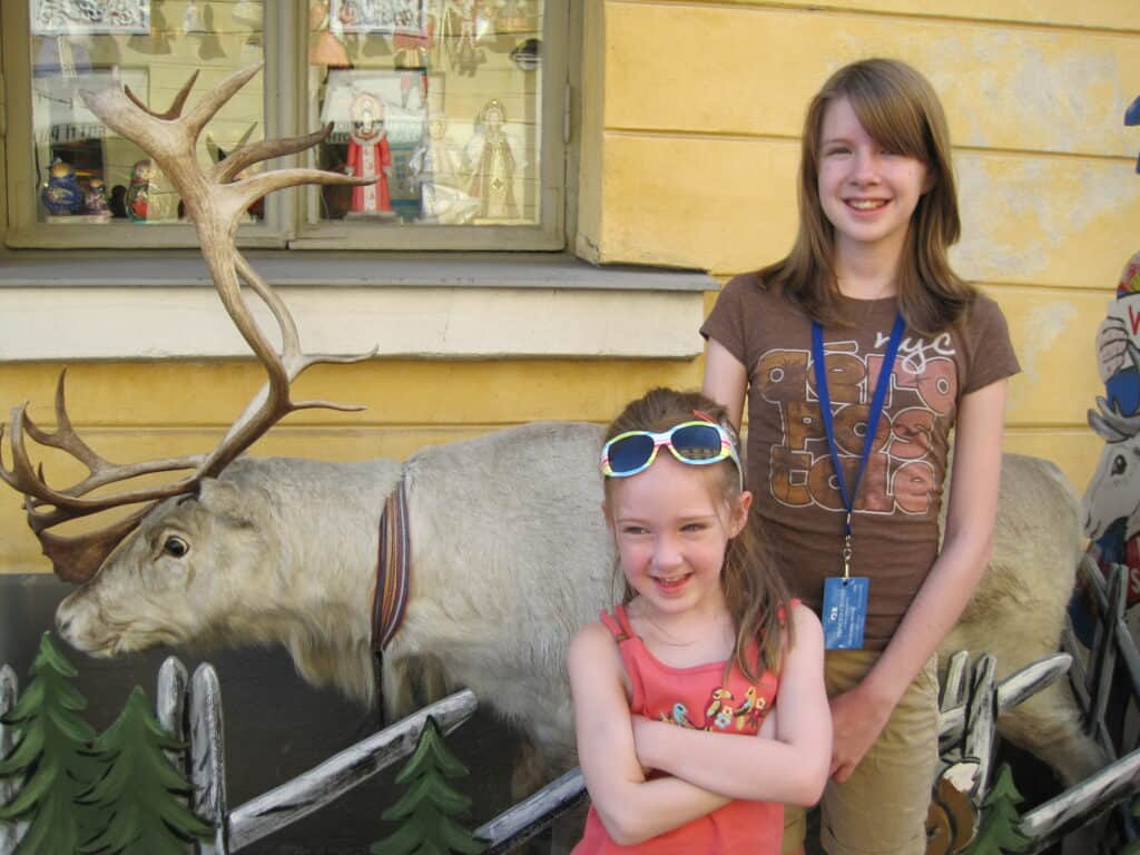 Young girls posing with a "reindeer" outside a tourist shop in Helsinki, Finland.