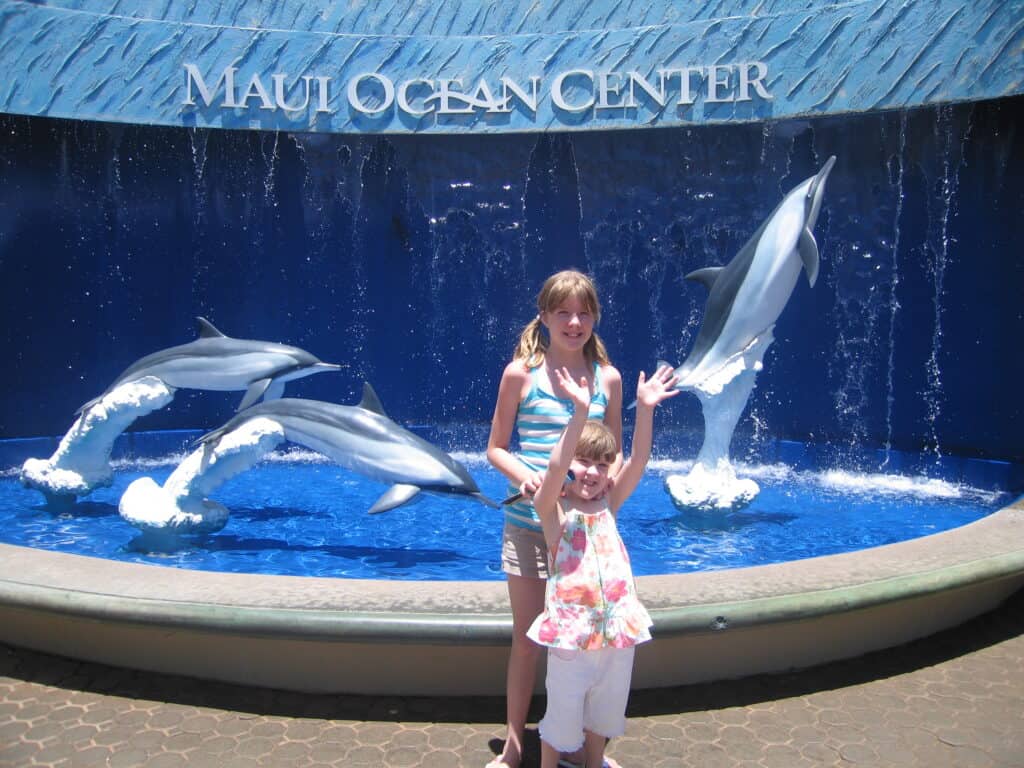 Two girls posing in front of dolphin fountain outside Maui Ocean Center in Maui.