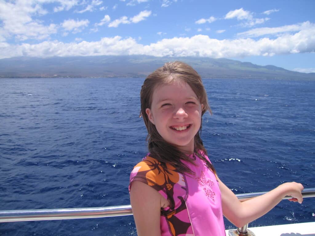 Young girl in pink flowered bathing suit poses on board boat on trip to Molokini Crater.