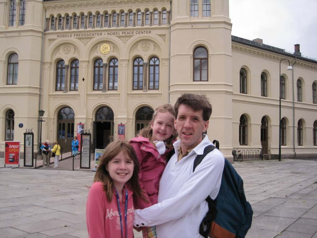 Dad and two daughters standing in front of the Nobel Peace Center in Oslo, Norway.