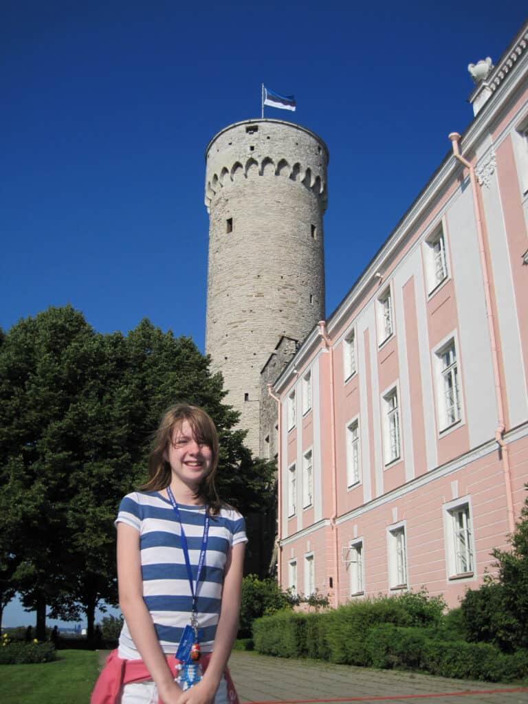 Young girl in blue and white striped t-shirt posing in front of pink coloured building - Toompea Castle in Tallinn, Estonia.