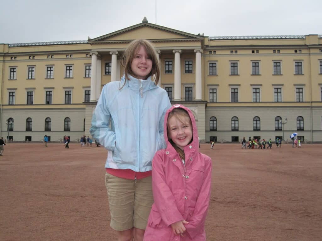 Two girls standing outside the Royal Palace in Oslo, Norway on an overcast day.