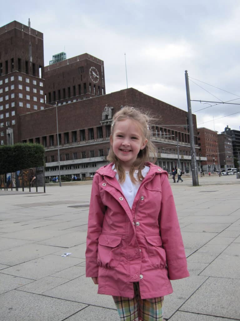 Young girl in pink jacket outside Radhuset (City Hall) in Oslo, Norway.