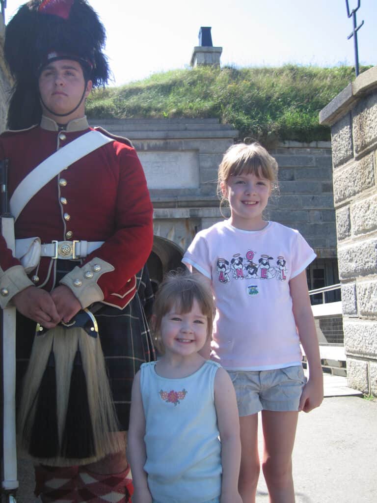 Two young girls posing with guard at the entrance to the Halifax Citadel.