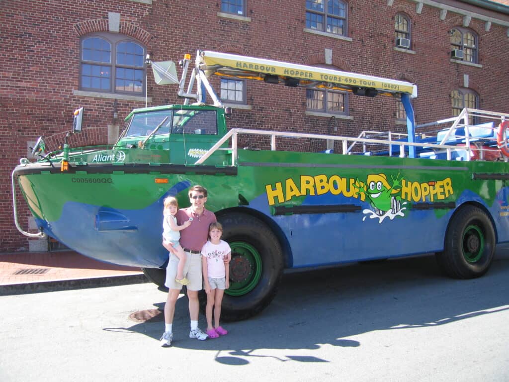 Dad and two young girls pose in front of Harbour Hopper in Halifax, Nova Scotia.