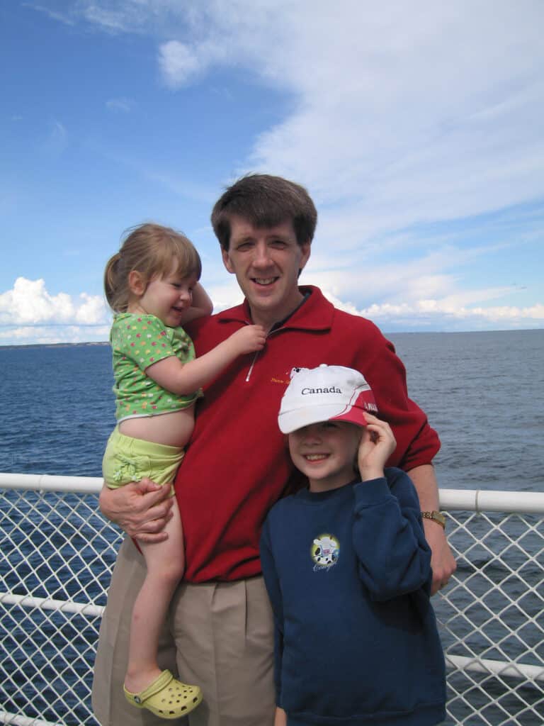 Young girl with dad holding toddler girl on ferry from nova scotia to prince edward island.