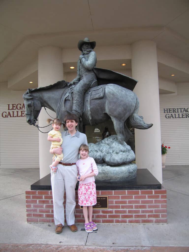 Man and two young girls posing in front of statue in Old Town Scottsdale, Arizona.