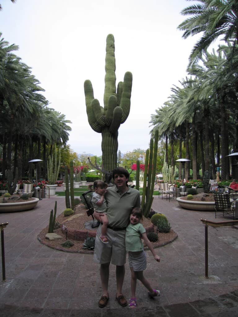 Man posing with two young girls in front of large saguaro cactus at Hyatt Regency in Scottsdale, Arizona.