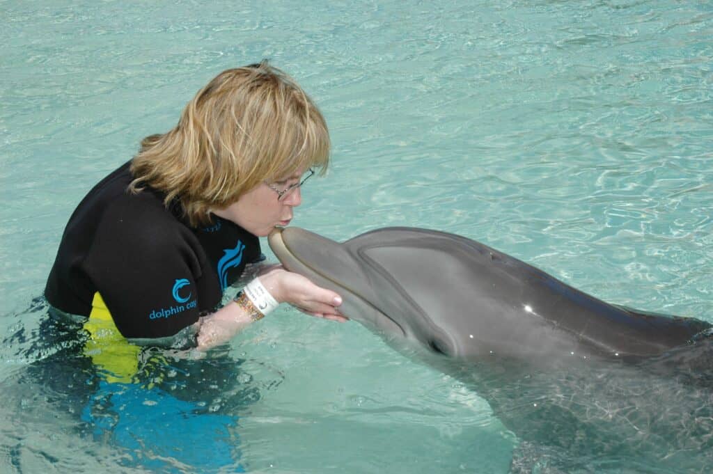 Woman kissing dolphin at Atlantis Bahamas Dolphin Cay.