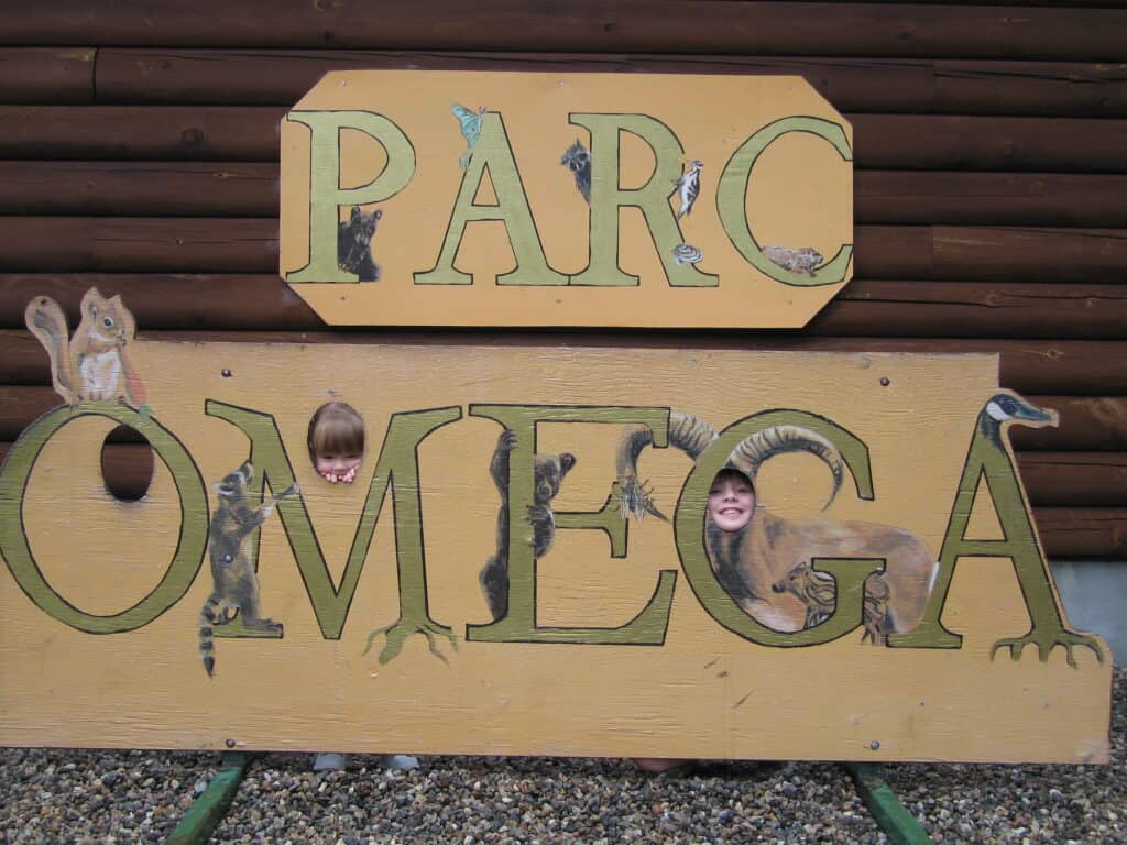 Yellow Parc Omega sign with green lettering and pictures of animals with two young girls faces in cut-outs.