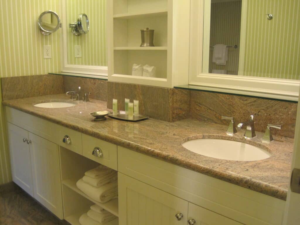 Rosseau Muskoka - large bathroom vanity countertop with two large mirrors, two sinks, cupboards, drawers and bathroom products on countertop - green striped wallpaper.