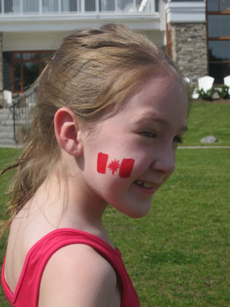 young girl in red tank top with canada flag painted on cheek - rosseau muskoka resort.