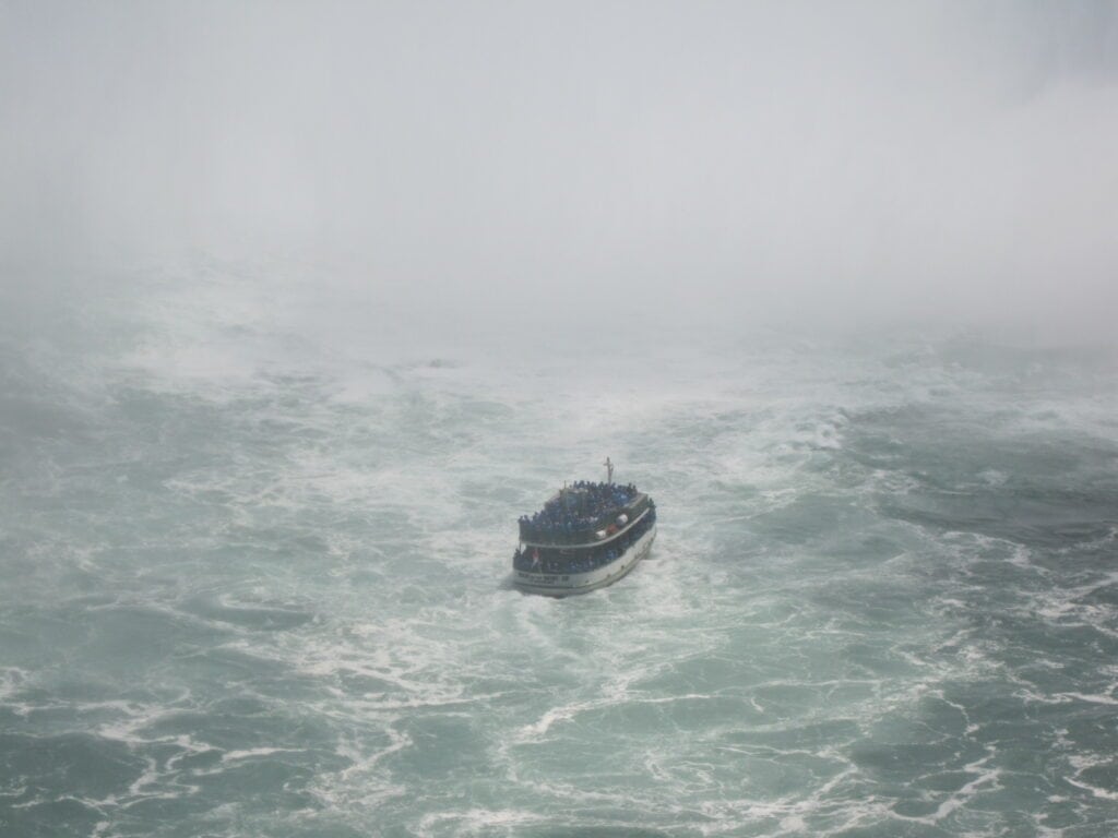 boat in churning waters of basin of horseshoe falls.