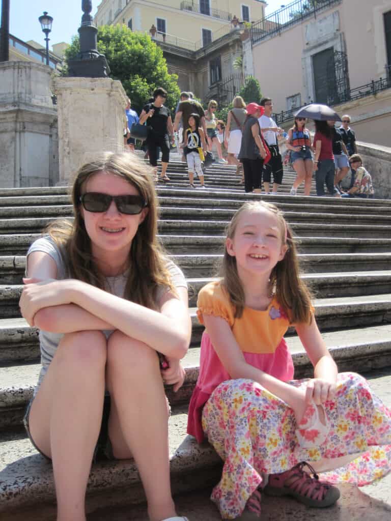 teen girl and younger girl sitting on spanish steps in rome.