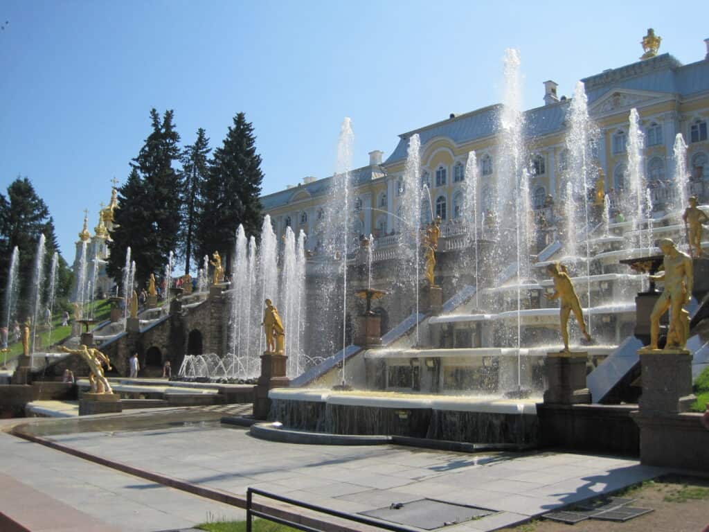 Fountains in Peterhof Palace Gardens, St. Petersburg, Russia on a sunny summer day - Grand Cascade viewed from lower terrace with Peterhof Palace in background.