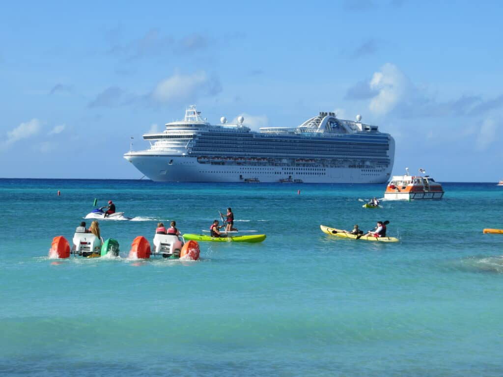 People in kayaks and other watercrafts in water in front of Crown Princess cruise ship anchored off Princess Cays in Bahamas.