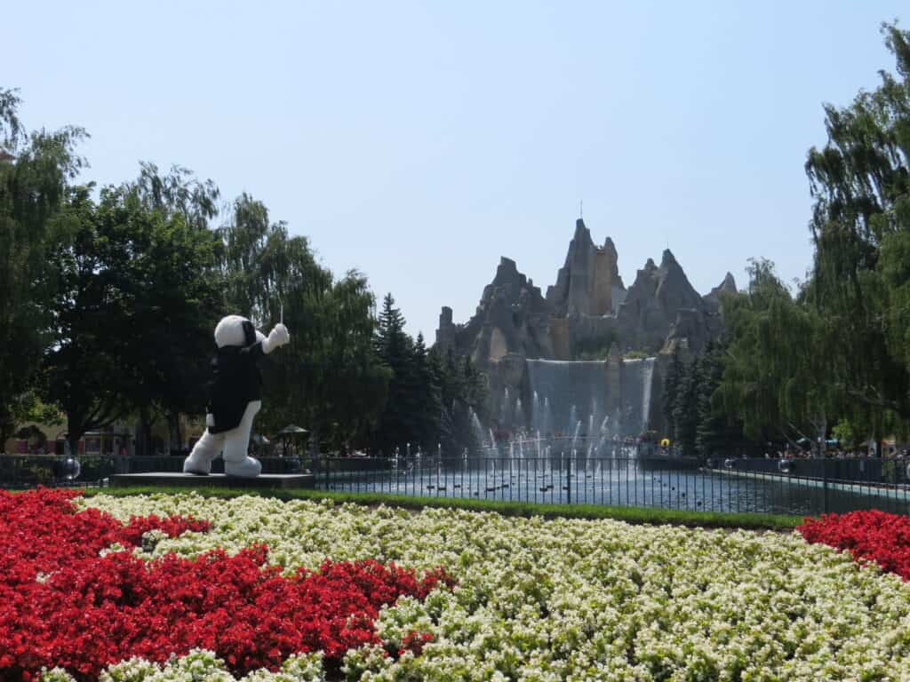 Snoopy wearing black jacket conducting music for water show in front of the mountain at Canada's Wonderland.