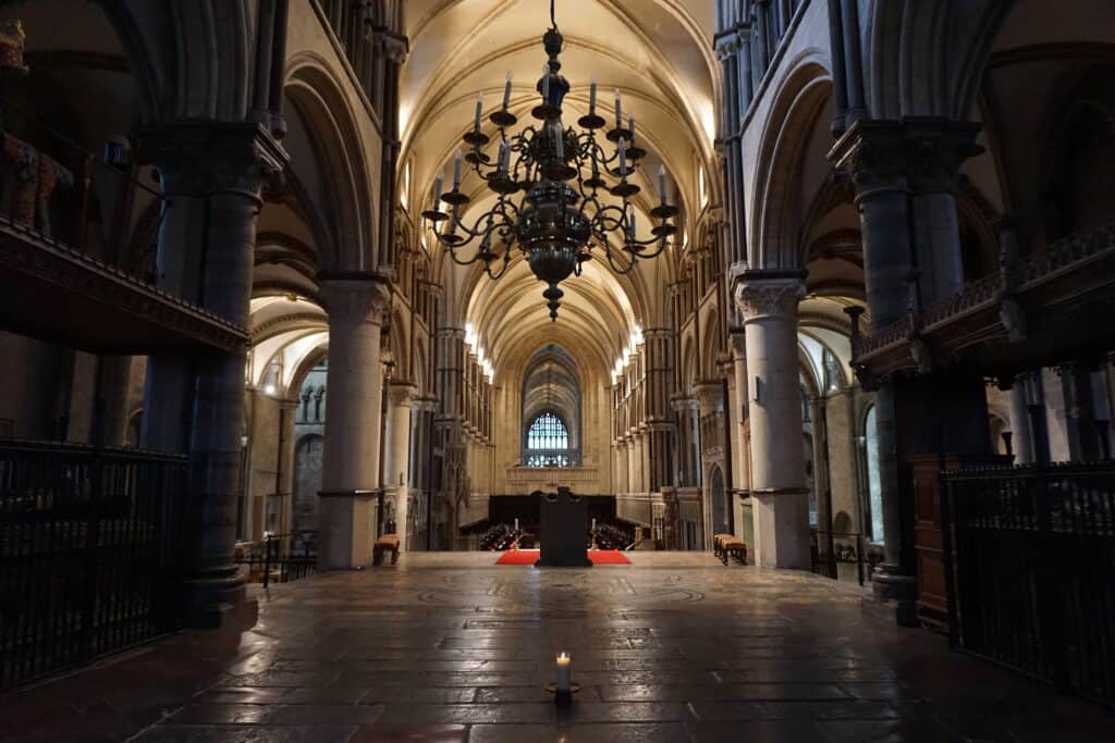 Thomas Beckett memorial at Canterbury Cathedral - burning candle sitting in centre of floor under candelabra in darkened church.