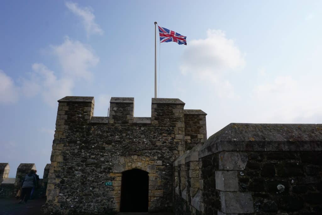 United Kingdom flag flying atop stone tower at Dover Castle.