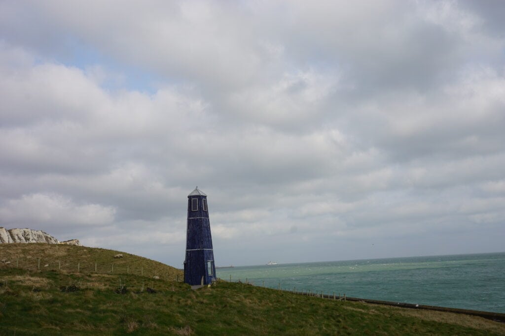 Cloudy  day at Cliffs of Dover - dark tower on grassy hill with sea in the background.