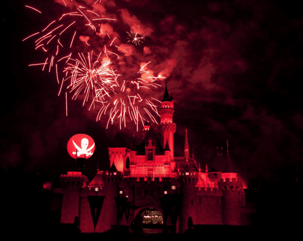 Halloween fireworks show at Disneyland with orange/red coloured lighting on castle and fireworks.