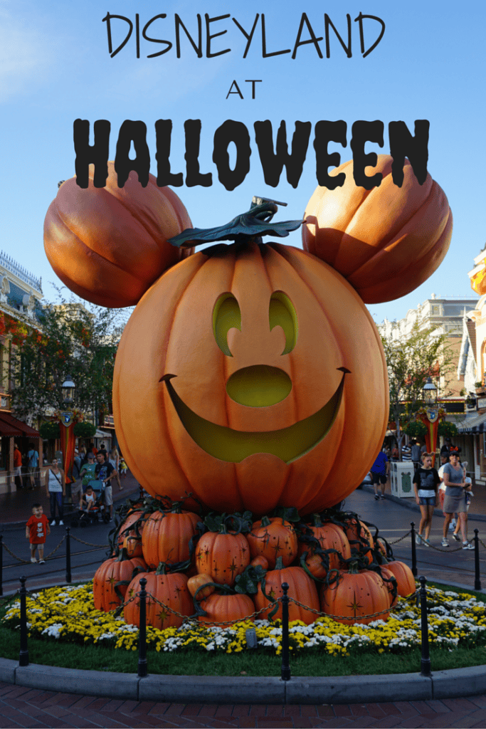 Pinterest image for Disneyland at Halloween with large Mickey jack-o-lantern on base of pumpkins at entrance to Main Street USA in Disneyland.