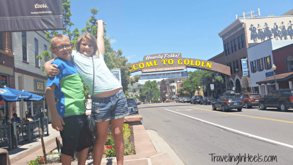 Boy and girl posing alongside street with Welcome to Golden sign in background.