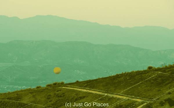 Large orange balloon floating over Great Park in Irvine, California.