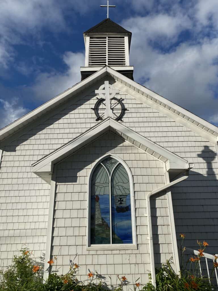 Front exterior of white church with blue stained glass window - St. John the Evangelist - the Sailor's Church - in Kagawong, Manitoulin Island, Ontario, Canada.