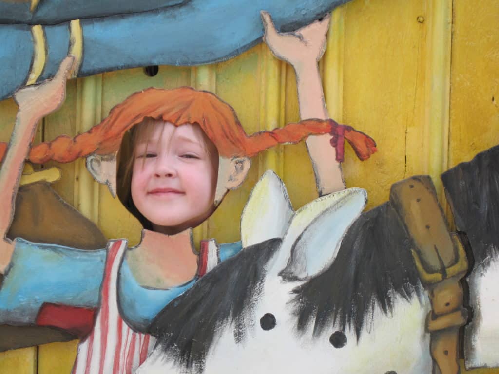 Young girl with face in cut-out of Pippy Longstocking at Junibacken Museum in Stockholm, Sweden.