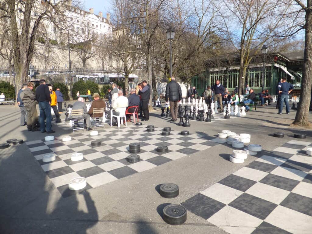 People standing around life-size chess boards in Bastions Park, Geneva.