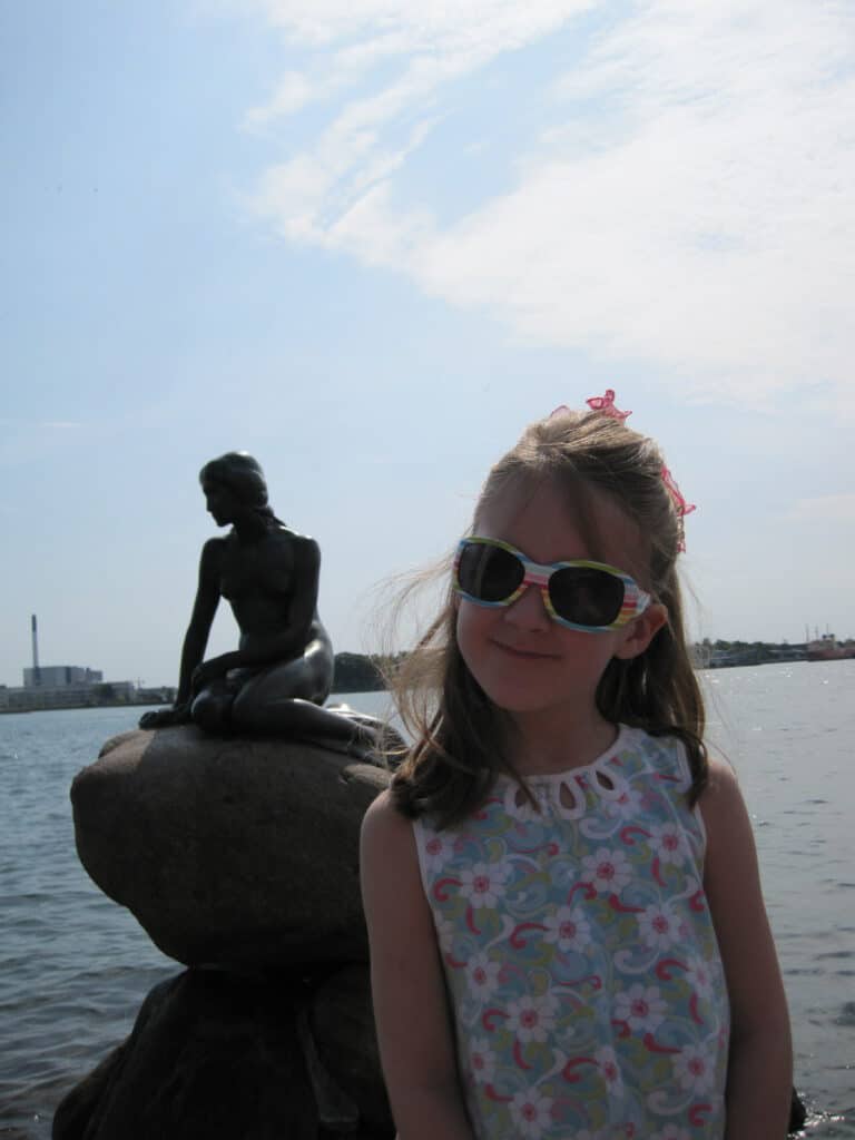 Young girl posing in front of the Little Mermaid statue in Copenhagen, Denmark.