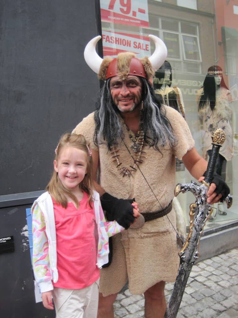Young girl standing with a man dressed as a Viking in Copenhagen.