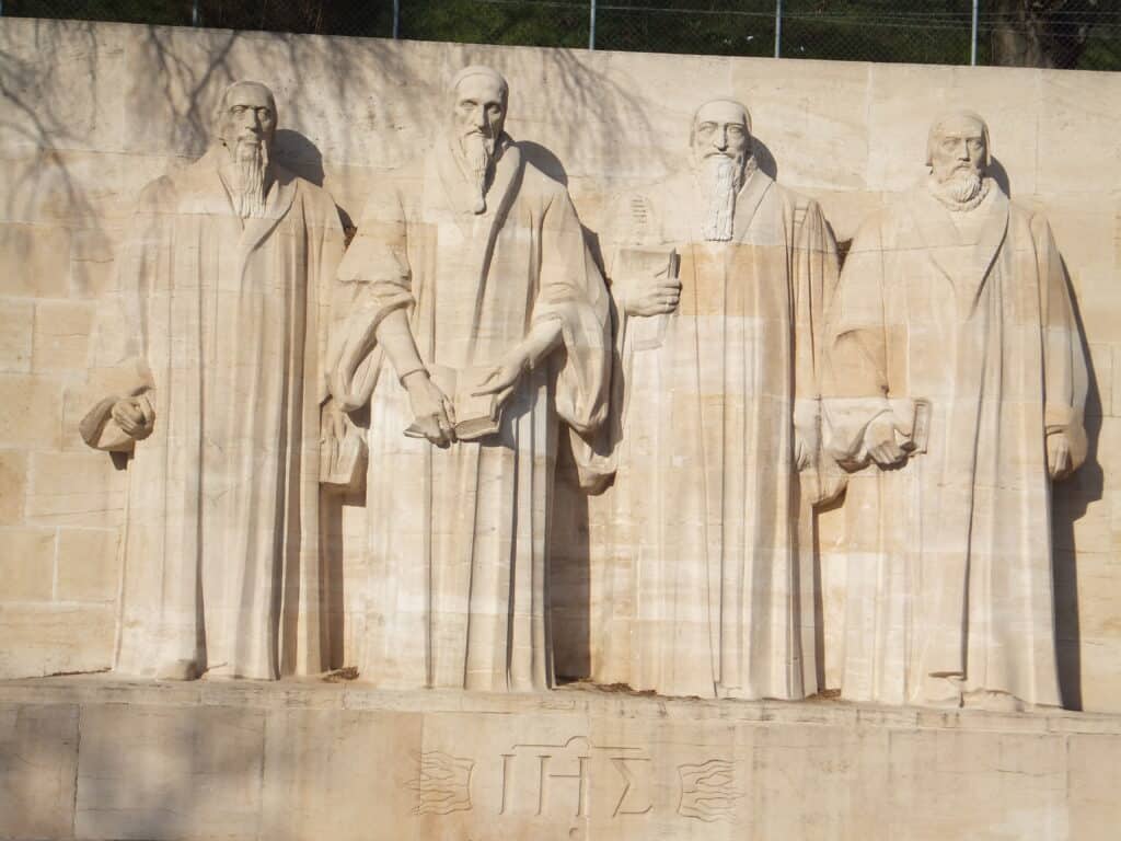 Four figures carved in the stone of the Reformation Wall in Geneva.