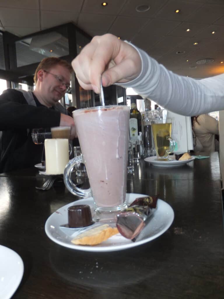 Stirring large glass of Swiss hot chocolate.