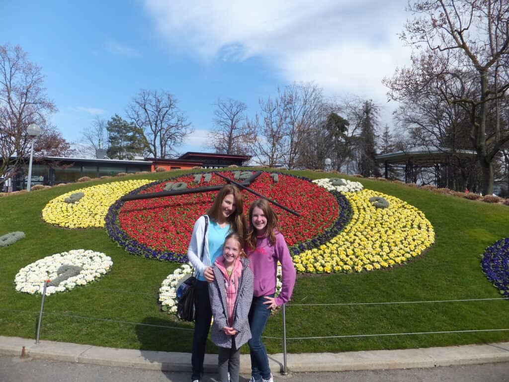 Two teen girls and a younger girl posing in front of Geneva's Floral Clock.