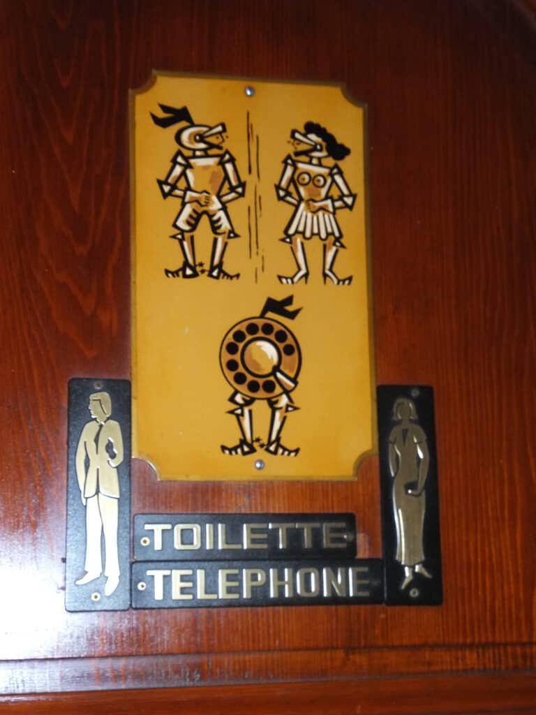 Toilet and telephone sign at Hotel Les Arumures with illustrations for men, women and telephone stylized as knights in armour.