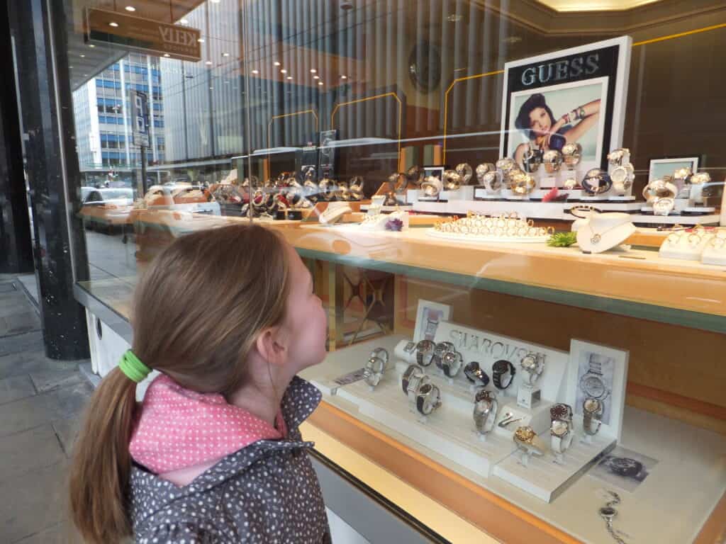 Young girl with ponytail looking at display of watches in a shop window in Geneva.