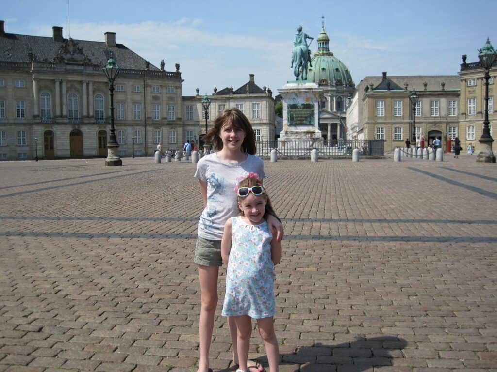Two young girls standing in courtyard of Amalienborg Palace in Copenhagen, Denmark.
