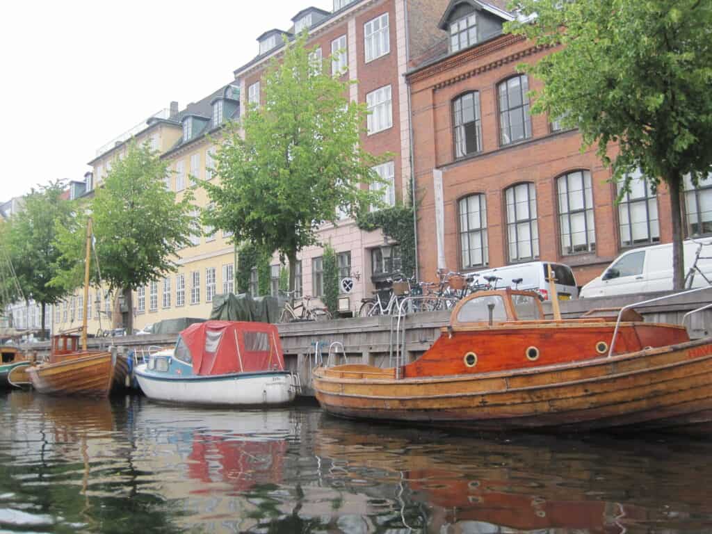 Boats moored along canal in Copenhagen with buildings in background.