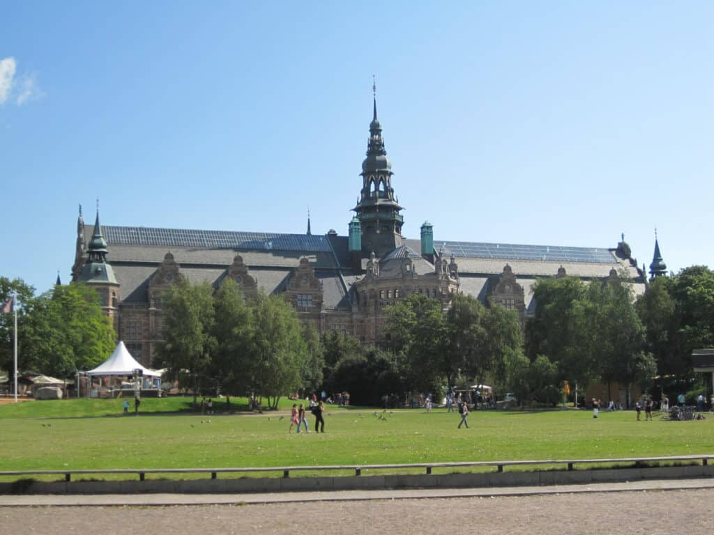 People walking on lawn in front of Nordic Museum in Stockholm.