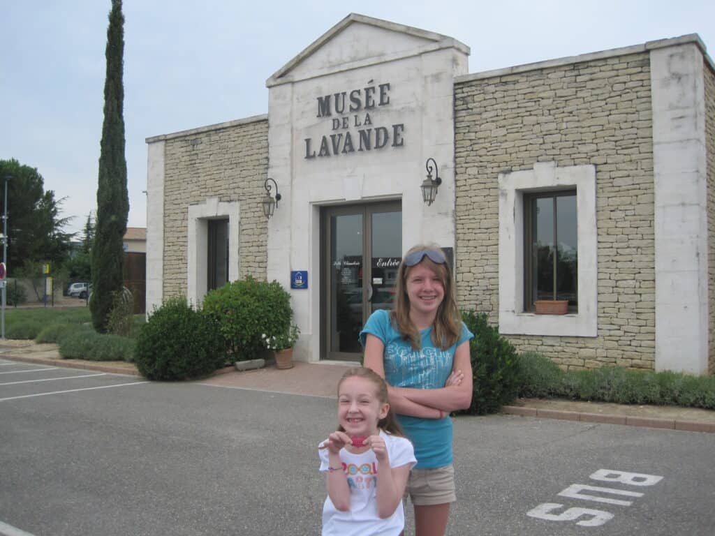 Teen girl and younger girl standing outside the Lavender Museum in Gordes, France.
