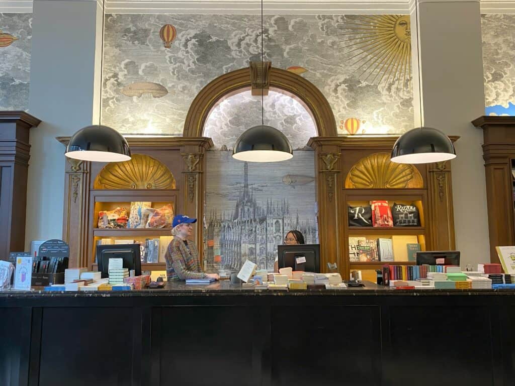 Two employees standing behind counter at Rizzoli Bookstore in New York City.