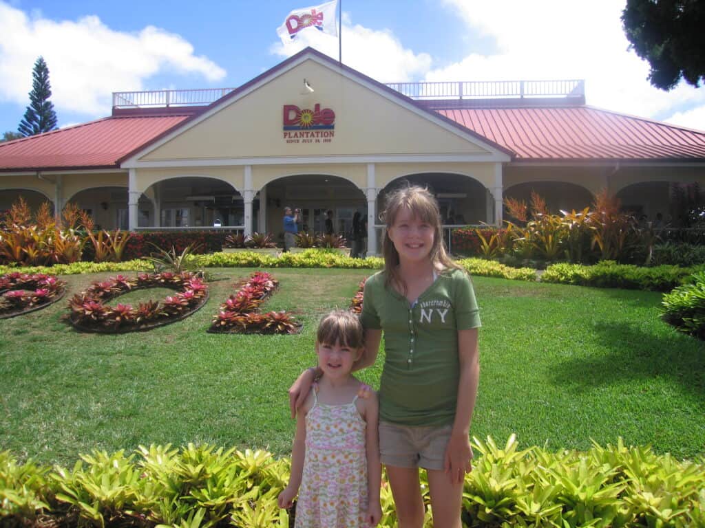 Two girls standing in front of the Dole Plantation building, Oahu, Hawaii.