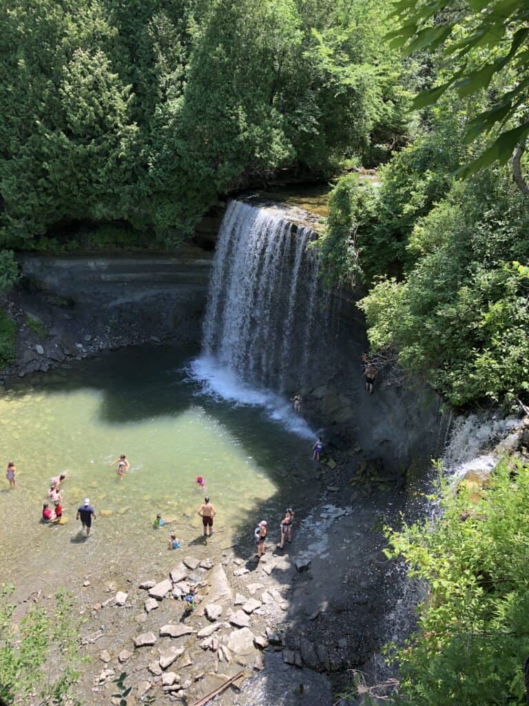 View looking down at people playing in water in front of Bridal Veil Falls, Kagawong, Manitoulin Island.