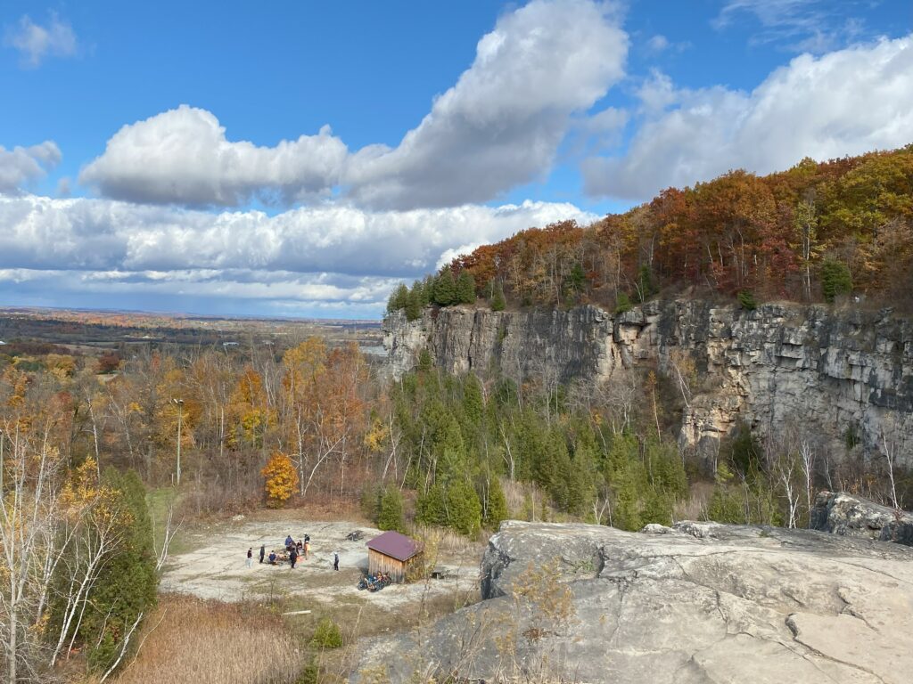 View of rocky Niagara Escarpment at Kelso Conservation Area on fall day with orange and yellow leaves.