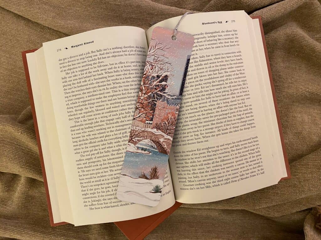 Bookmark depicting winter scene in Central Park in New York City sitting on top of an open book.