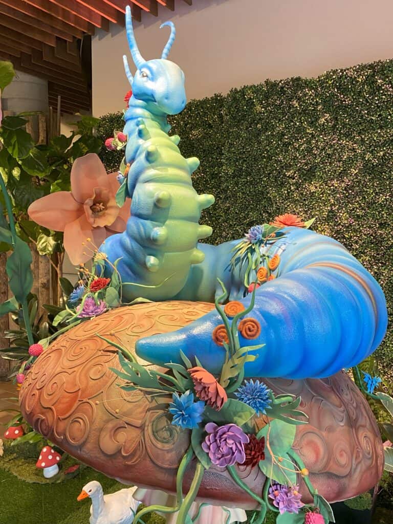 Large display of blue and green caterpillar sitting on a toadstool - Alice in Bloomland - Royal Botanical Gardens.