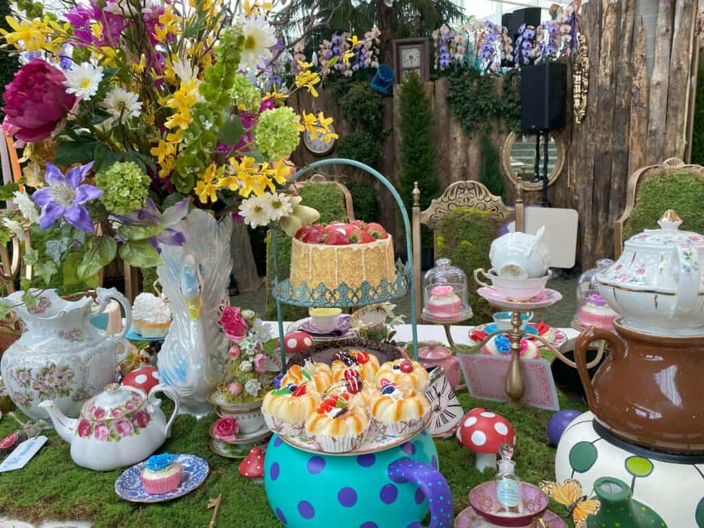 Tea pots, tea cups, cakes, treats, flowers on table set for tea as part of Alice in Bloomland display at the Royal Botanical Gardens.